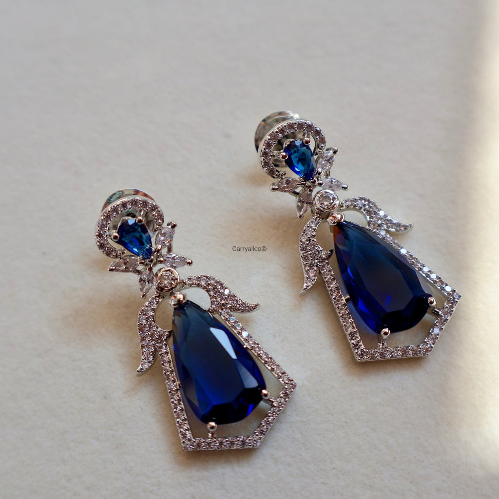 Pair of blue teardrop earrings with silver accents on a light background