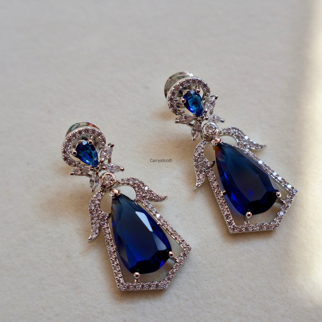 Pair of blue teardrop earrings with silver accents on a light background