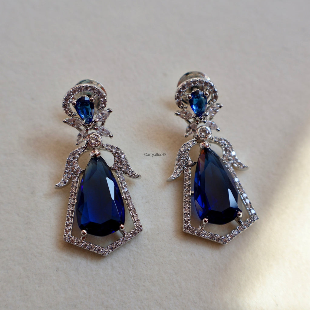 Pair of earrings with blue teardrop stones on a light beige background