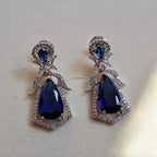Pair of earrings with blue teardrop stones on a light beige background