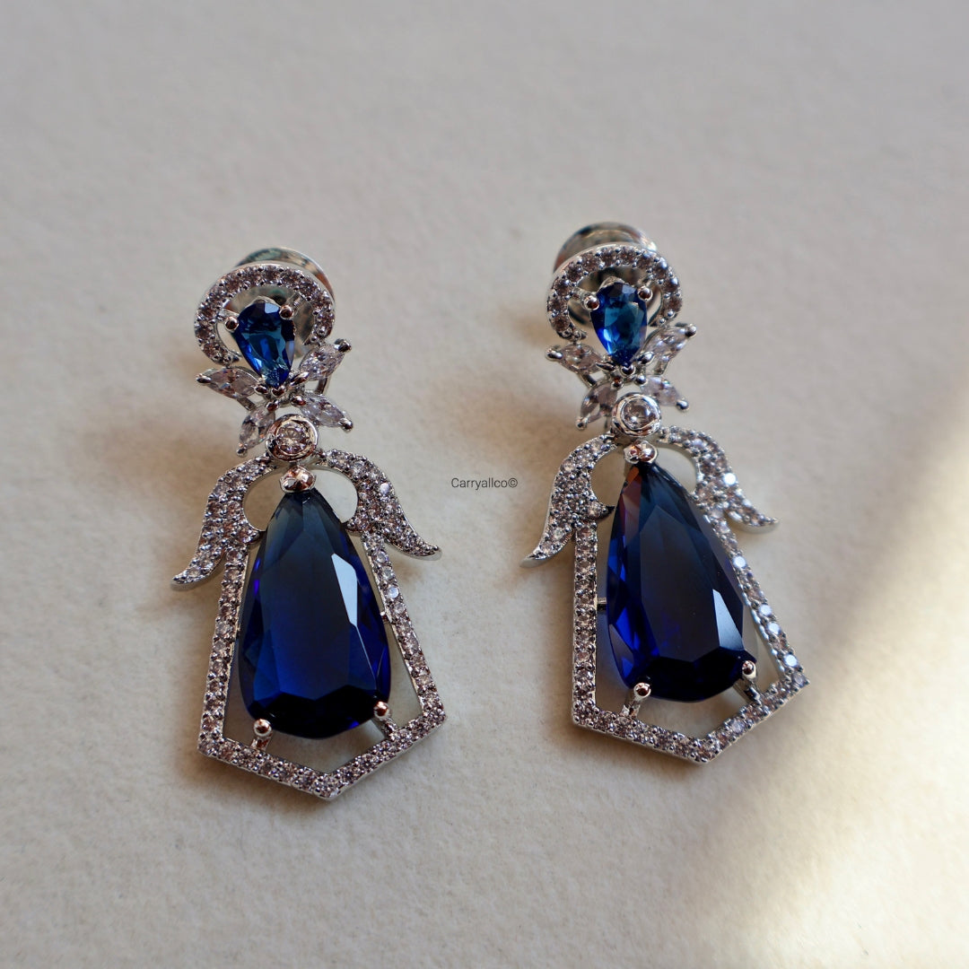 Pair of earrings with blue teardrop stones on a light beige background