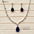Jewelry set with necklace and earrings featuring blue teardrop stones on a wooden surface.