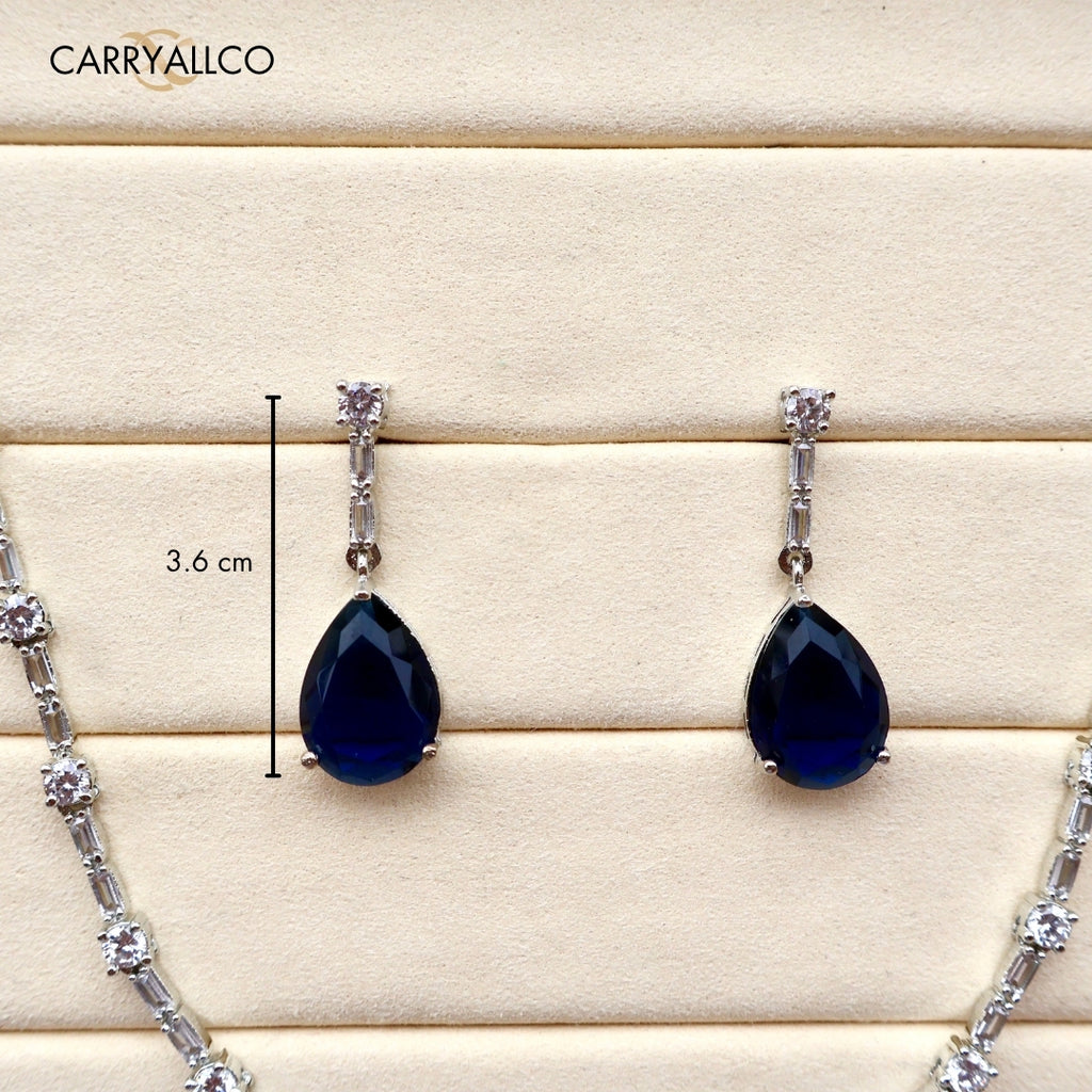 Teardrop-shaped black gemstone earrings with silver accents on a wooden surface, featuring the brand 'CARRYALICO'.