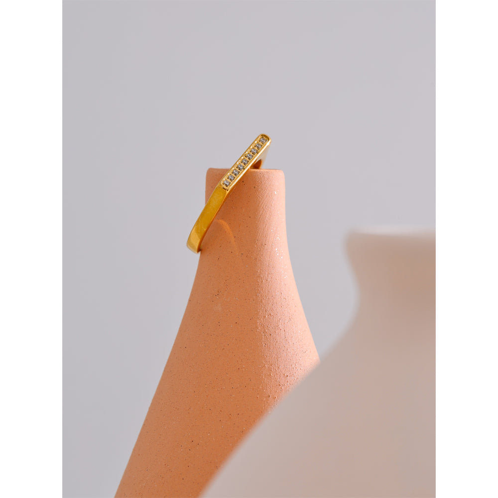 Gold ring on a terracotta stand against a light gray background