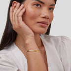 Woman wearing a gold bracelet on a plain background