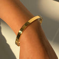 Gold bracelet on a person's wrist with a neutral background