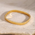 Gold bracelet on a textured beige surface