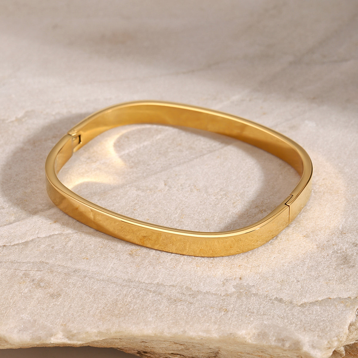 Gold bracelet on a textured beige surface
