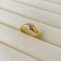 Gold ring with embedded stones on a beige fabric background