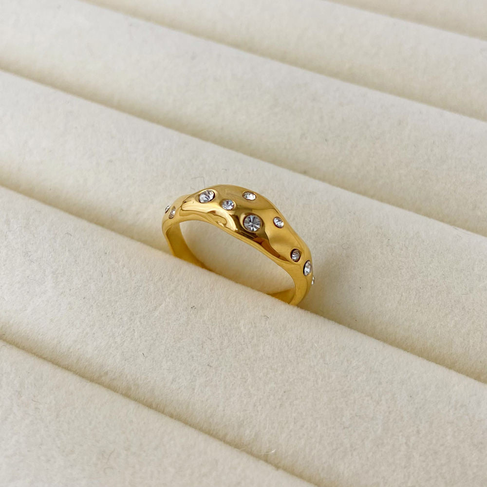 Gold ring with embedded stones on a beige fabric background