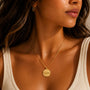 Close-up of a woman wearing a gold necklace with a pendant.
