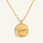 Gold necklace with a zodiac pendant on a light beige background