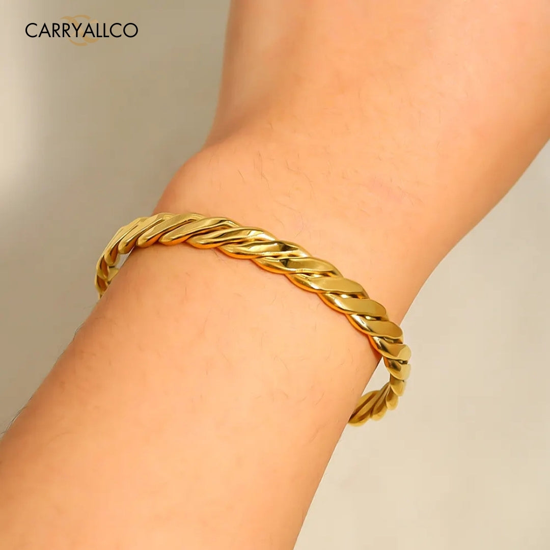 Gold braided bracelet on a wrist with a neutral background
