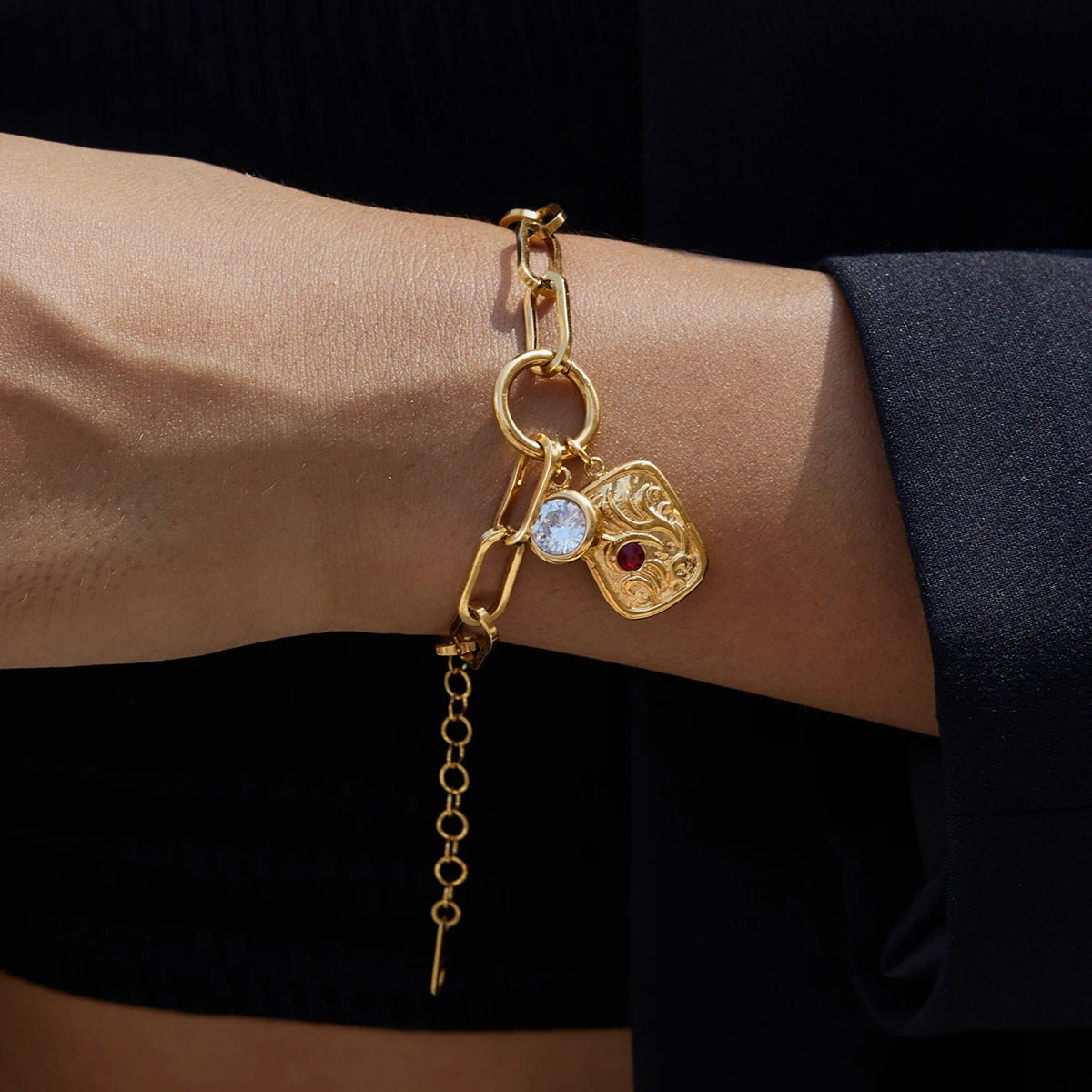 Gold bracelet with charms on a wrist against a black background