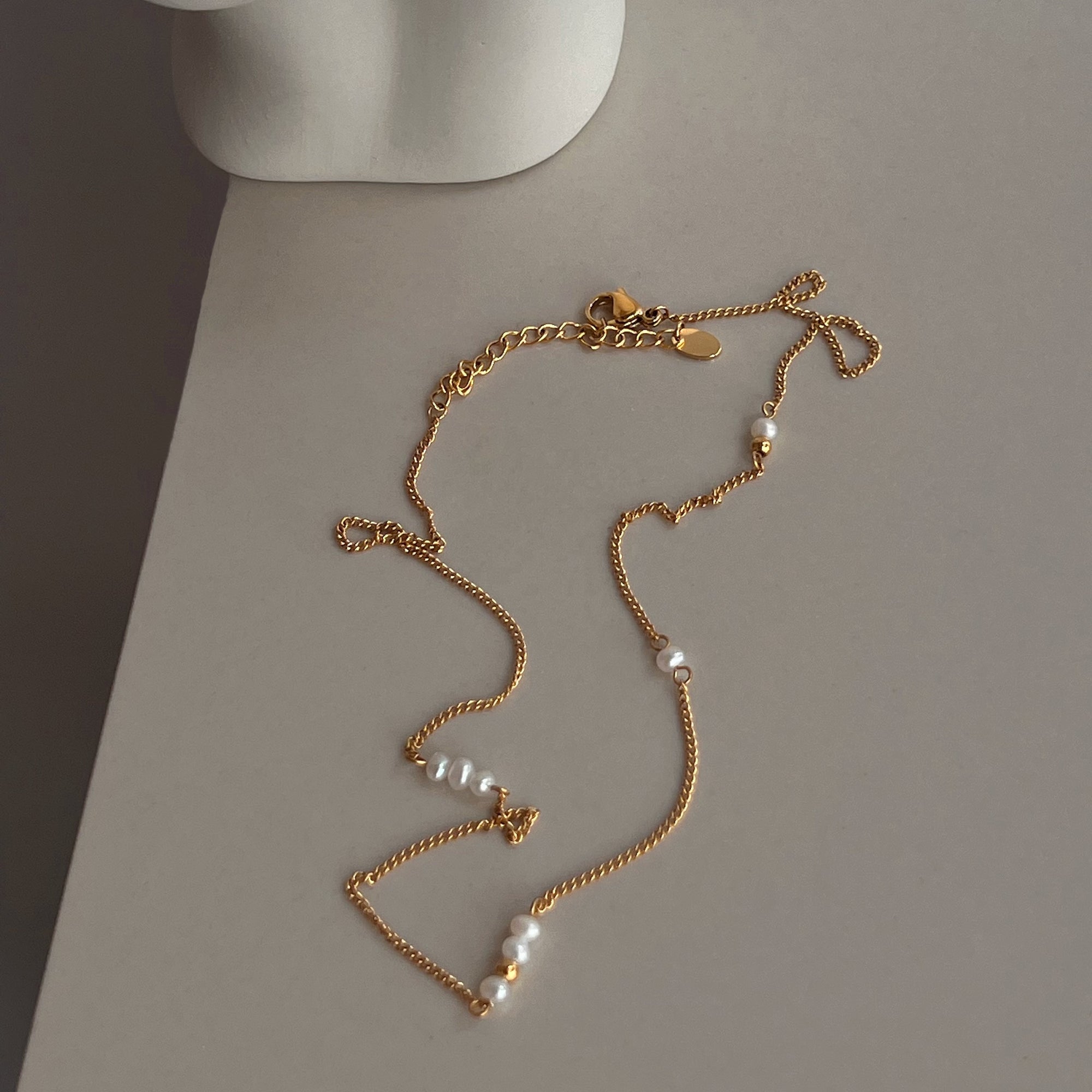 Gold necklace with pearls on a gray surface