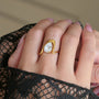 Gold ring with a large diamond on a hand wearing black lace gloves.