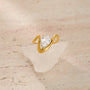 Gold ring with a pear-shaped diamond on a textured beige surface
