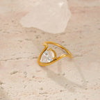 Gold ring with a heart-shaped diamond on a textured beige surface