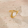 Gold ring with a diamond on a textured beige surface