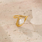 Gold ring with a diamond on a textured beige surface