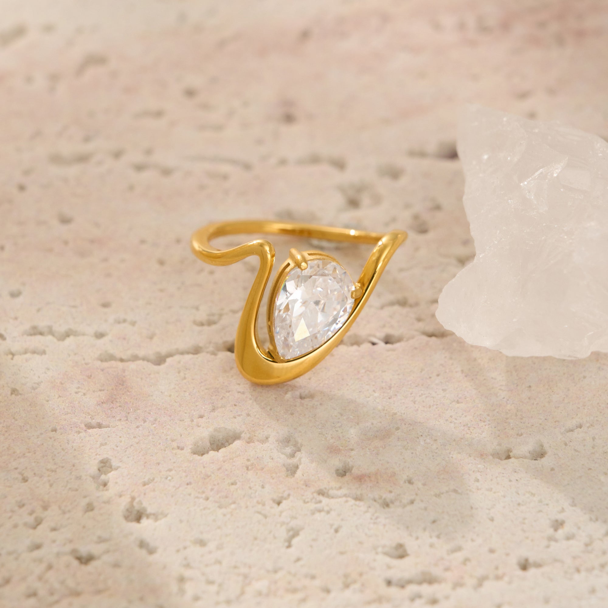Gold ring with a diamond on a textured beige surface
