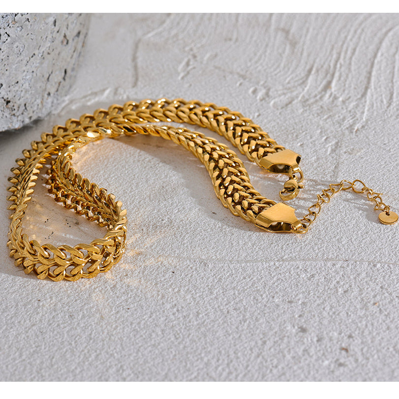 Gold chain bracelet on a textured light gray surface