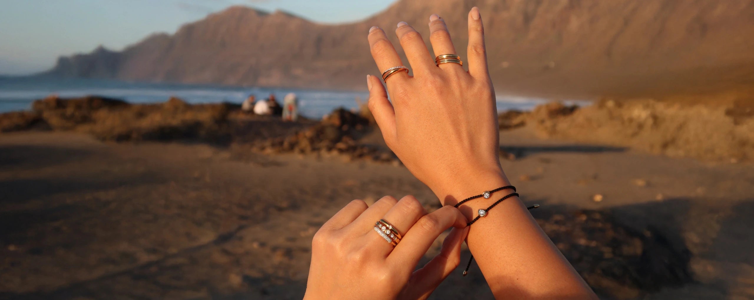 Hands with rings on a beach at sunset