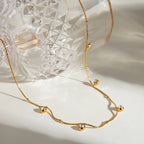 Gold necklace with small spherical pendants on a light background