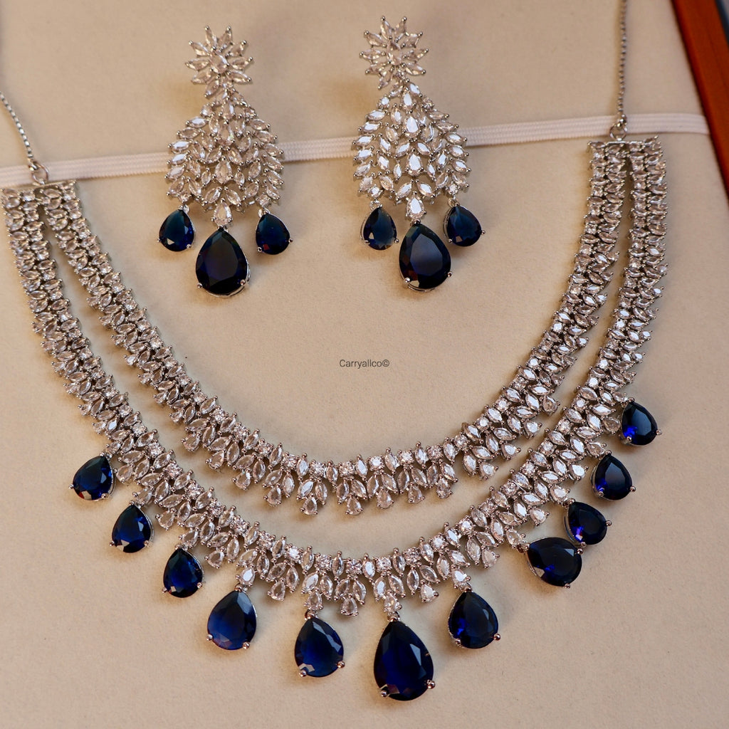 Silver necklace with blue stones and matching earrings on a beige background