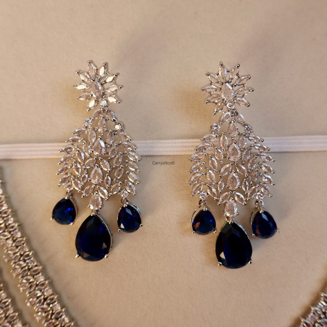 Pair of silver earrings with blue teardrop stones on a beige background