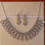 Silver necklace and earrings set on a beige background
