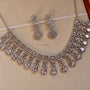 Silver necklace and earrings set on a beige background