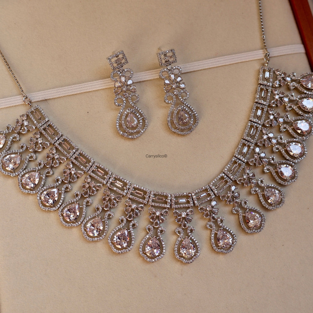 Silver necklace and earrings set on a beige background