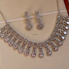 Silver necklace and earrings set on a beige background